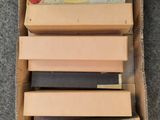 une boîte remplie de livres de toutes sortes, posée sur un tapis