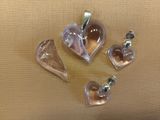 three glass heart shaped pendants on a beige cloth