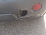 the rear end of a car with a hole in the bumper
