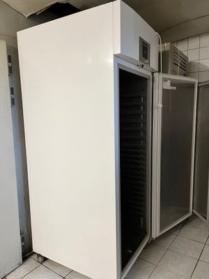 un réfrigérateur blanc au milieu d'un sol carrelé