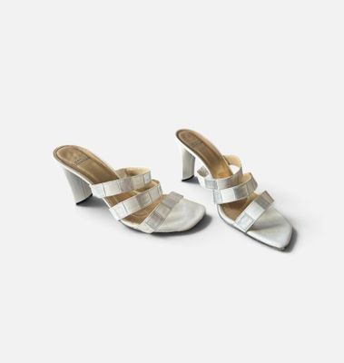 une paire de mules en cuir argenté avec des lanières au niveau des orteils