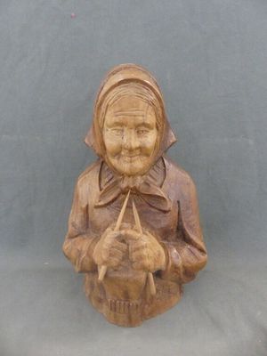 statue en bois sculpté représentant une femme tenant un chat, sur fond bleu