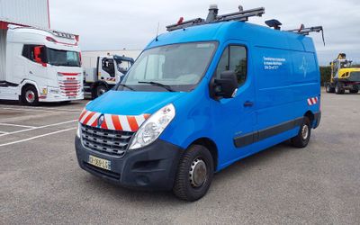 une camionnette bleue garée sur un parking, avec d'autres camions en arrière-plan
