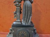 a statue of a woman holding a clock on top of a table