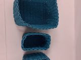 three blue crocheted baskets sitting on top of a white surface