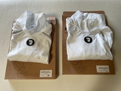 pair of white t - shirts in boxes on a white surface