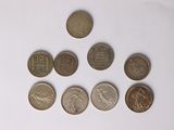 six different coins are arranged in a row on a white surface