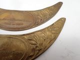 two antique brass spoons are sitting on a white surface