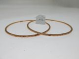 deux bracelets en or posés sur un fond blanc, avec une étiquette de prix