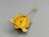 broche plaquée or représentant une tortue sur le dos, avec une feuille au centre