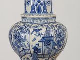 a blue and white vase with a bird on top of it