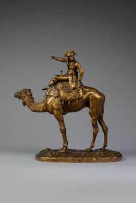 bronze statue of a man riding a camel with a hat on his head