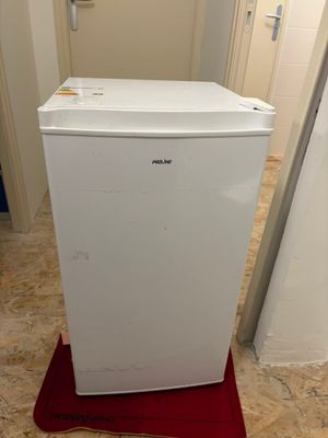 un réfrigérateur blanc posé sur un tapis rouge dans une pièce