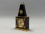 une horloge noire et or posée sur une surface blanche