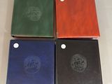 four different colored notebooks sitting on top of a white surface