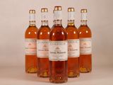 six bouteilles de vin sont alignées sur une surface blanche