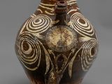 vase marron et blanc orné de motifs en spirale sur un fond gris