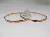 deux bracelets rigides en or ornés de motifs gravés sur un fond blanc