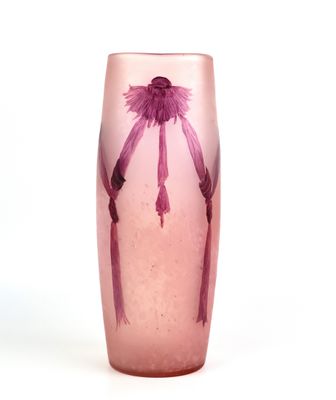 un vase en verre violet contenant une fleur rose, posé sur une surface blanche