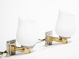 two white glass lamps on a gold plated wall mounted light