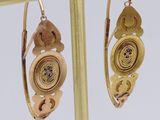 a pair of earrings that are on a gold stand