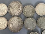 six different types of silver coins on a gray surface