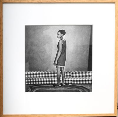 black and white photograph of a young girl standing on a bed