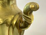 a large gold vase with a bird on the handle