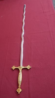 une épée posée sur une table recouverte d'une nappe rouge
