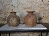 deux vases posés sur une table devant un mur de pierre