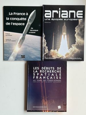 trois livres posés sur une surface blanche, avec une navette spatiale en arrière-plan
