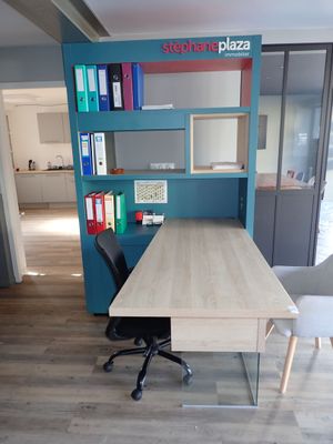 a desk with a chair and a book shelf in the corner