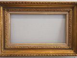 an old picture frame hanging on a wall with a white wall in the background