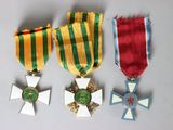 three medals and a cross on a white surface