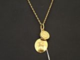 Gros plan sur un collier en or sur lequel se trouve une pièce de monnaie