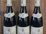 trois bouteilles de vin sont alignées sur une étagère en bois