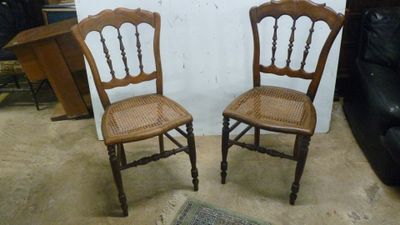 une paire de chaises anciennes en bois avec des dossiers en rotin dans un salon