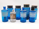 Plusieurs bouteilles contenant un liquide bleu sont alignées sur une surface blanche