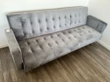 grey velvet tufted sofa in a room with wood flooring