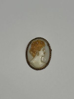 un camée blanc et doré représentant une femme aux cheveux bouclés