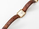 a gold plated wrist watch with a brown leather strap