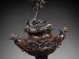 a large bronze incense pot with a dragon on top of it