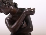 bronze statue of a young boy holding his hands on his chest
