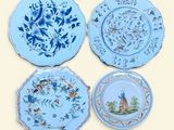 four plates with blue and white designs on them on a yellow background