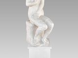 a white marble statue of a woman sitting on a rock