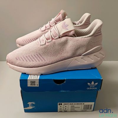 a pair of pink sneakers sitting on top of a blue box