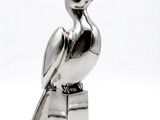 a silver statue of a bird sitting on top of a block