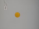 a gold coin sitting on a white surface next to a price tag