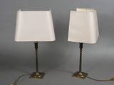 pair of brass table lamps with white lampshads on each of them