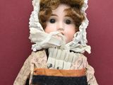 an antique doll of a woman in a dress and bonnet